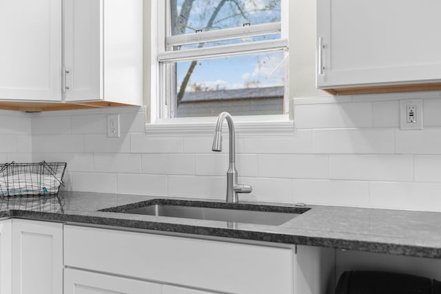 kitchen featuring white cabinets, tasteful backsplash, dark stone counters, and sink