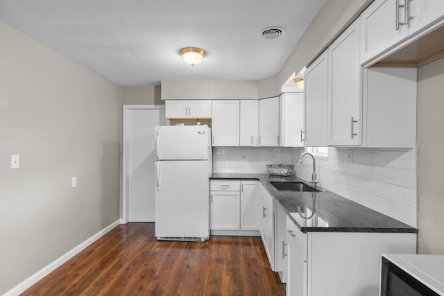 kitchen with tasteful backsplash, sink, white cabinets, white fridge, and dark hardwood / wood-style floors