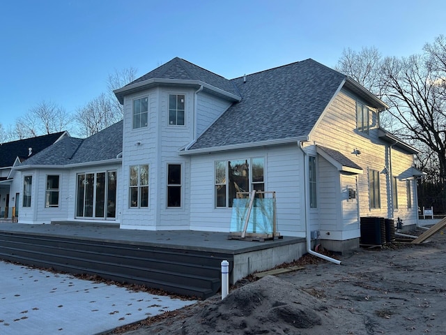 back of house with roof with shingles and a deck