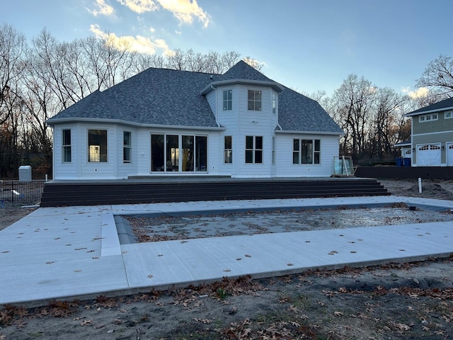 back of house with a shingled roof and a deck