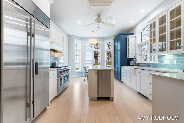 1749 Sunset Point Dr, Norton Shores, MI 49441 - kitchen featuring premium appliances, a center island, ceiling fan, light wood-type flooring, and decorative backsplash