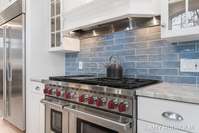 1749 Sunset Point Dr, Norton Shores, MI 49441 - kitchen with high quality appliances, custom exhaust hood, white cabinets, glass insert cabinets, and tasteful backsplash