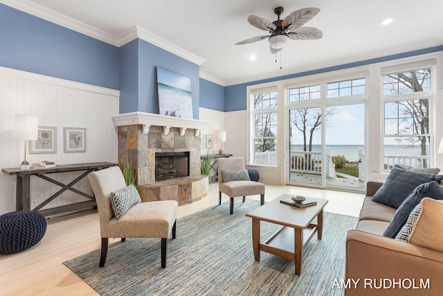 1749 Sunset Point Dr, Norton Shores, MI 49441 - living room featuring a fireplace with raised hearth, a ceiling fan, wood finished floors, ornamental molding, and a decorative wall