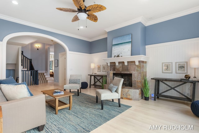 1749 Sunset Point Dr, Norton Shores, MI 49441 - living area featuring arched walkways, a ceiling fan, wood finished floors, a fireplace with raised hearth, and stairs