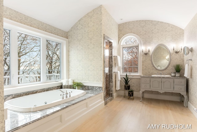 1749 Sunset Point Dr, Norton Shores, MI 49441 - full bathroom featuring vaulted ceiling, a tub with jets, wood finished floors, and vanity