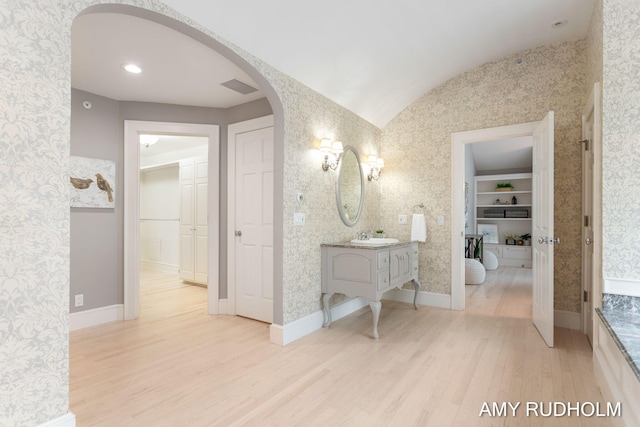 1749 Sunset Point Dr, Norton Shores, MI 49441 - bathroom with wallpapered walls, wood finished floors, vanity, baseboards, and vaulted ceiling