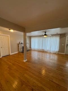 unfurnished living room with ceiling fan and dark wood-type flooring