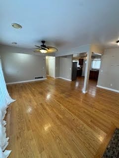 unfurnished living room featuring ceiling fan and dark hardwood / wood-style flooring