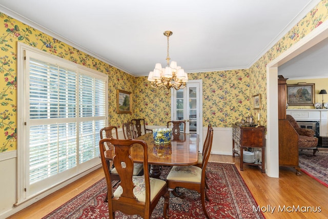 dining space featuring light wood-type flooring, ornamental molding, and an inviting chandelier