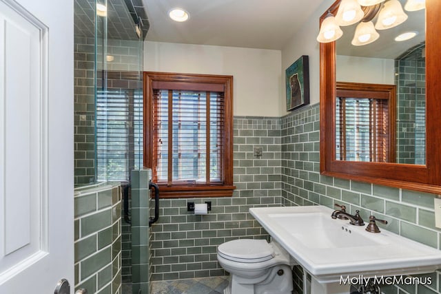 bathroom featuring toilet, plenty of natural light, tile walls, and sink