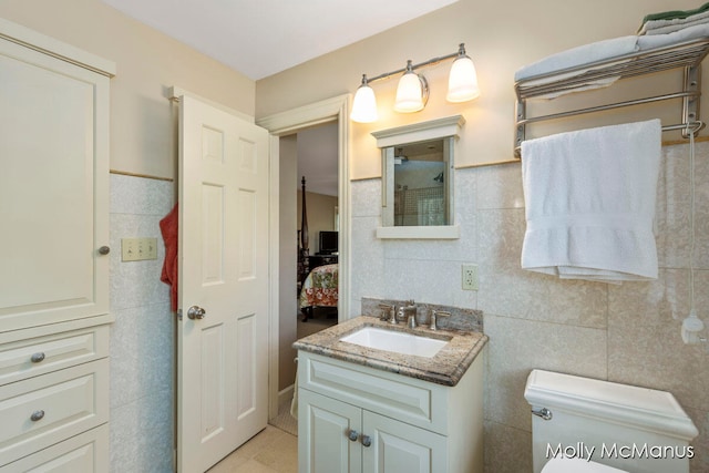 bathroom featuring tile patterned floors, vanity, toilet, and tile walls