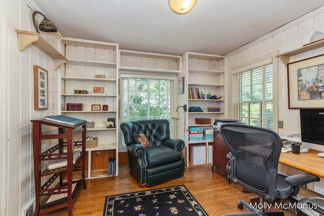 office area with hardwood / wood-style floors, a wealth of natural light, crown molding, and wood walls