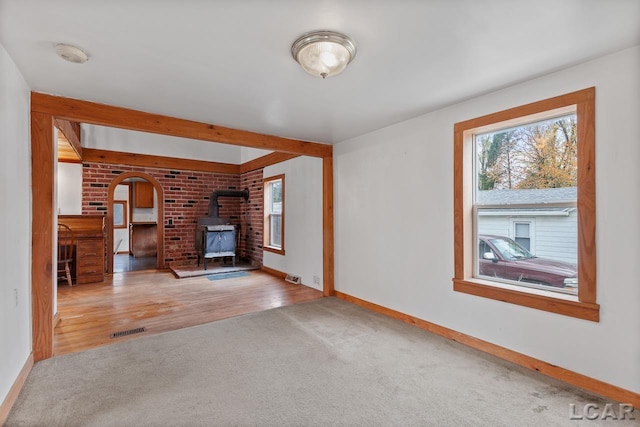 unfurnished living room with wood-type flooring and a wood stove