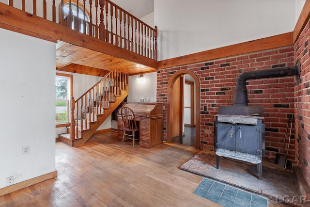 living room with wood-type flooring, a wood stove, and a high ceiling