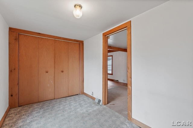 unfurnished bedroom featuring light carpet and a closet