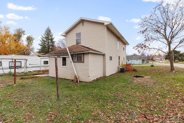 back of house with central AC unit and a lawn