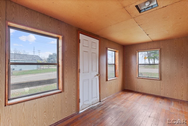 entrance foyer featuring hardwood / wood-style floors, plenty of natural light, and wooden walls