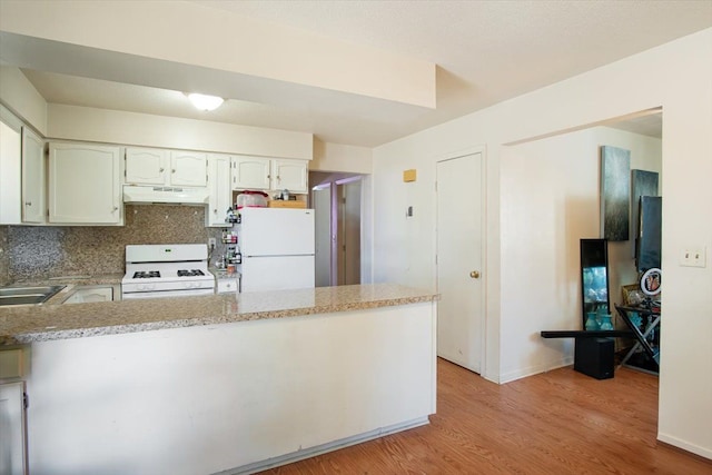 kitchen with kitchen peninsula, backsplash, white appliances, light hardwood / wood-style floors, and white cabinetry