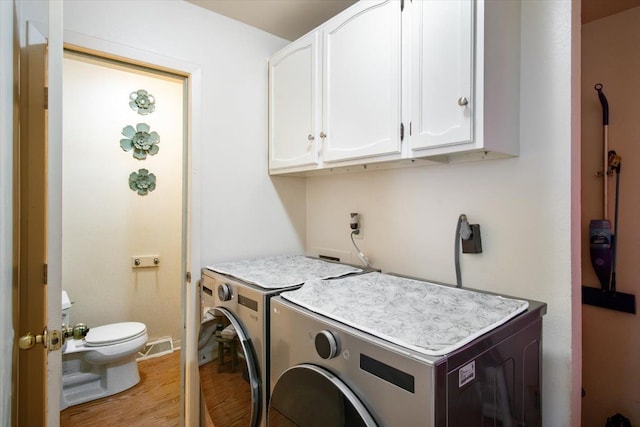 washroom featuring cabinets, light wood-type flooring, and independent washer and dryer