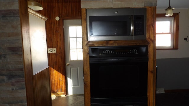 kitchen with black oven and wood walls