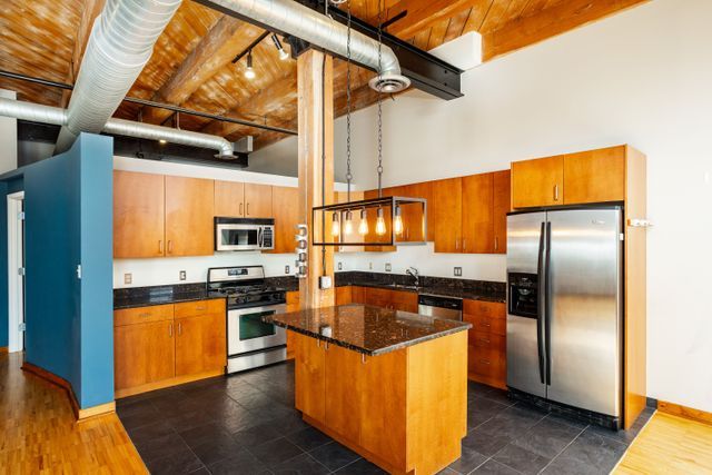 kitchen with wooden ceiling, sink, a towering ceiling, appliances with stainless steel finishes, and a kitchen island