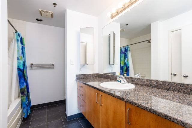 bathroom with tile patterned floors, vanity, and shower / bath combo with shower curtain