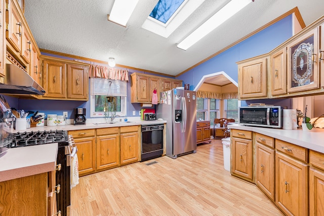 kitchen with stainless steel appliances, crown molding, plenty of natural light, and light hardwood / wood-style floors