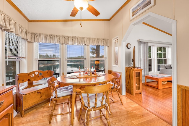 dining area with ornamental molding, lofted ceiling, and light wood-type flooring