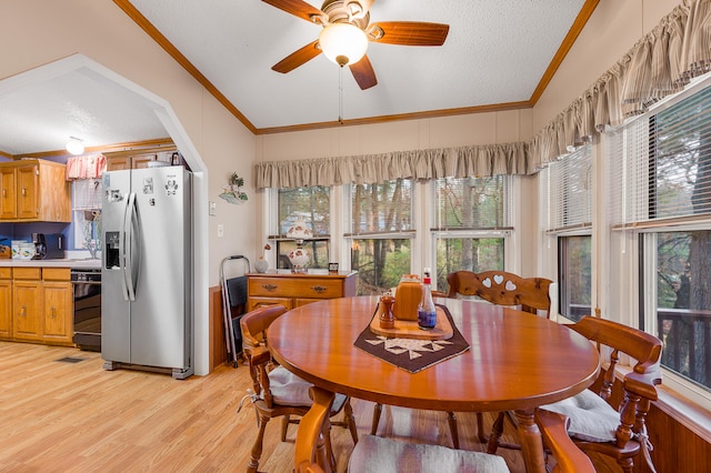 dining room featuring crown molding, vaulted ceiling, ceiling fan, light wood-type flooring, and a textured ceiling