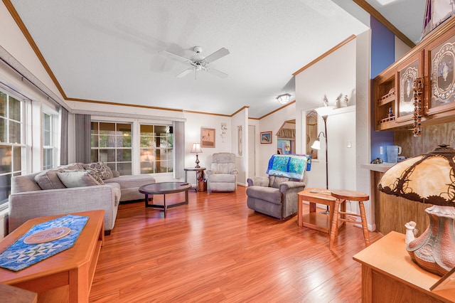 living room featuring wood-type flooring, a textured ceiling, ceiling fan, and ornamental molding