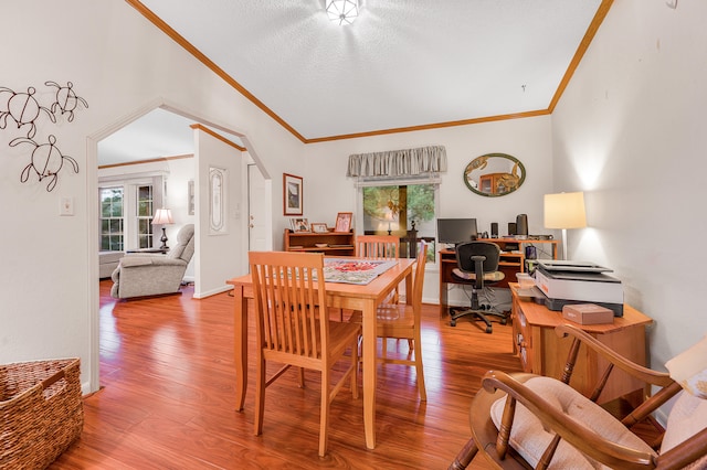 dining space featuring lofted ceiling, hardwood / wood-style flooring, and crown molding