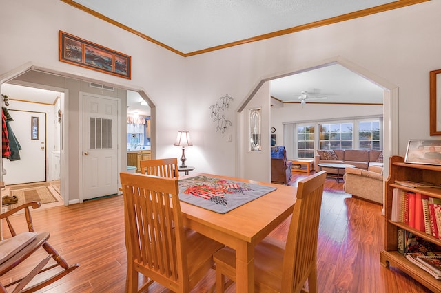 dining space with ceiling fan, wood-type flooring, lofted ceiling, and ornamental molding