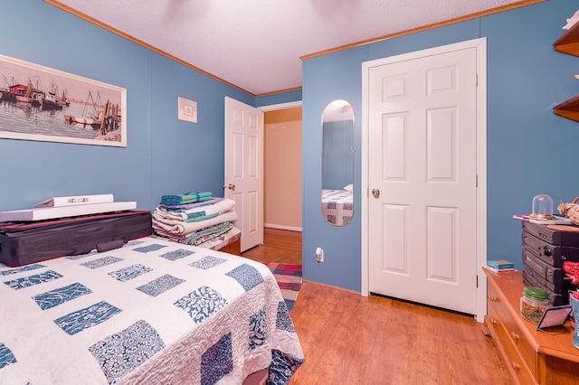 bedroom featuring ornamental molding, a textured ceiling, and light hardwood / wood-style flooring