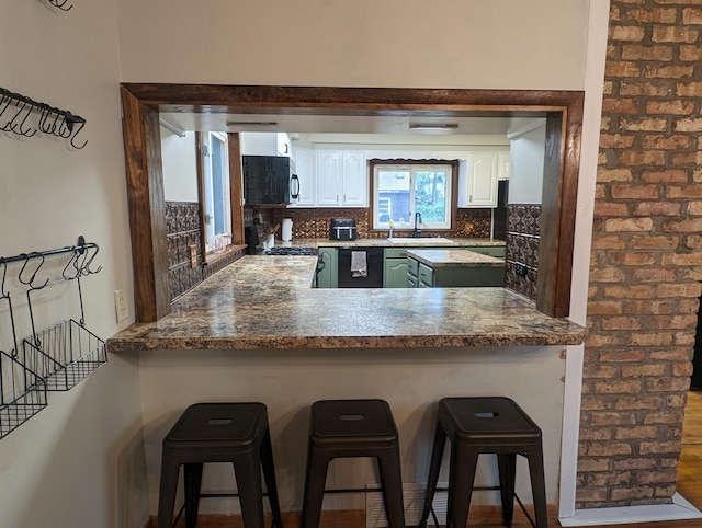 kitchen featuring a kitchen bar, decorative backsplash, sink, and white cabinetry