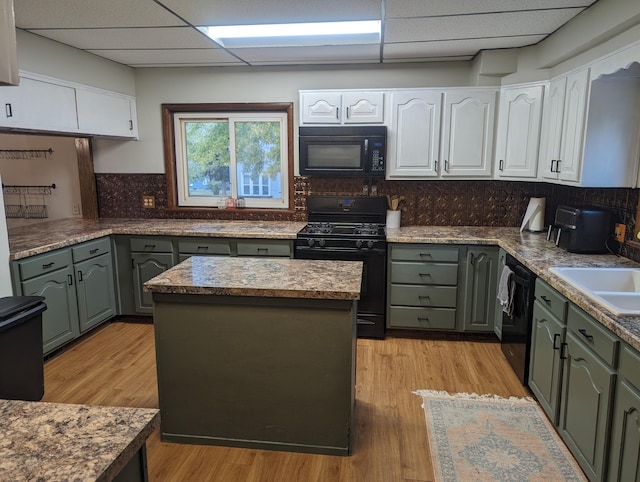 kitchen featuring backsplash, white cabinetry, a drop ceiling, and black appliances