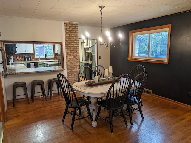 dining area featuring a chandelier, sink, and wood-type flooring