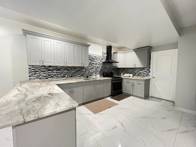 kitchen featuring gray cabinetry, black stove, wall chimney range hood, sink, and kitchen peninsula