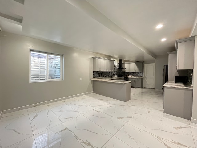 kitchen with stainless steel refrigerator, wall chimney exhaust hood, tasteful backsplash, kitchen peninsula, and gray cabinets