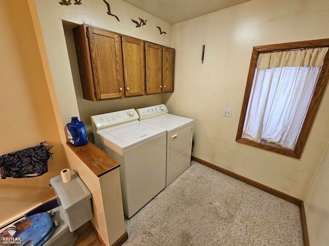 laundry room featuring separate washer and dryer, light colored carpet, and cabinets