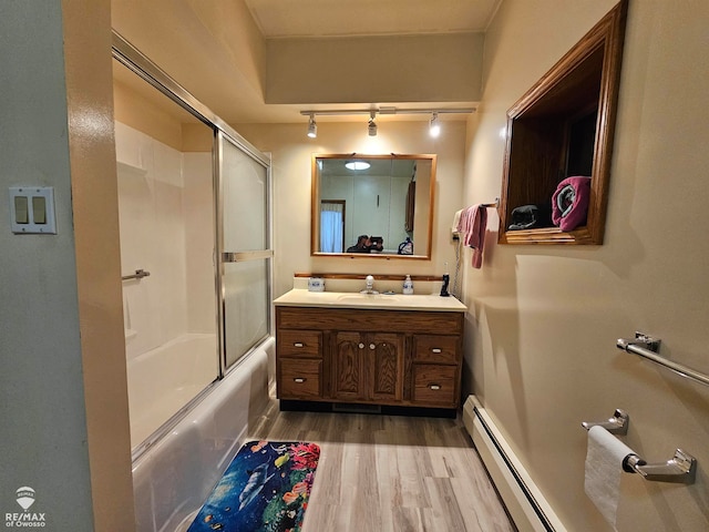 bathroom featuring vanity, wood-type flooring, a baseboard radiator, and combined bath / shower with glass door