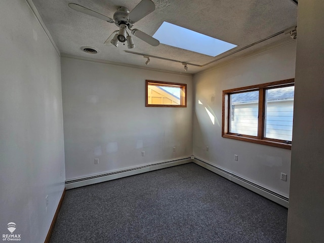 carpeted spare room featuring ceiling fan, baseboard heating, a textured ceiling, and a skylight