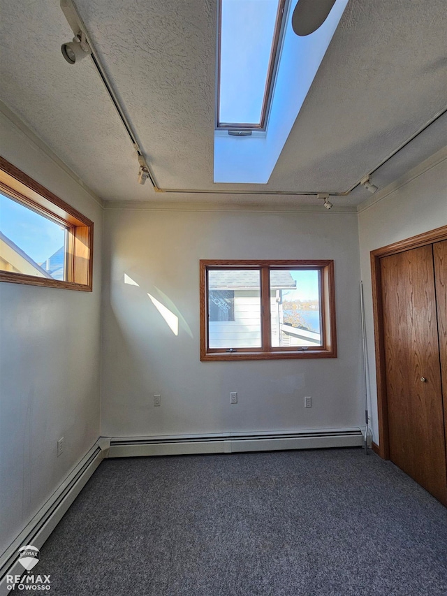 interior space featuring multiple windows, a textured ceiling, and dark colored carpet