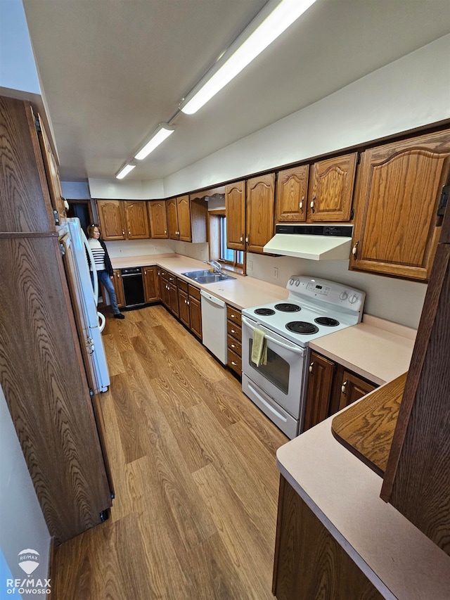 kitchen with sink, white appliances, and light wood-type flooring