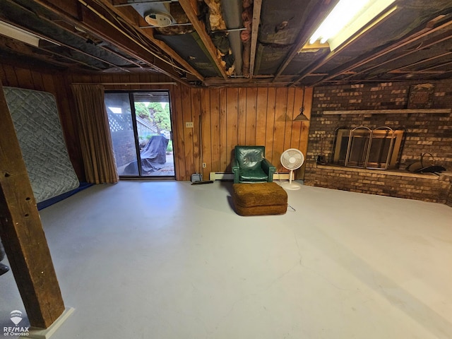 unfurnished room with wood walls, baseboard heating, brick wall, and concrete floors