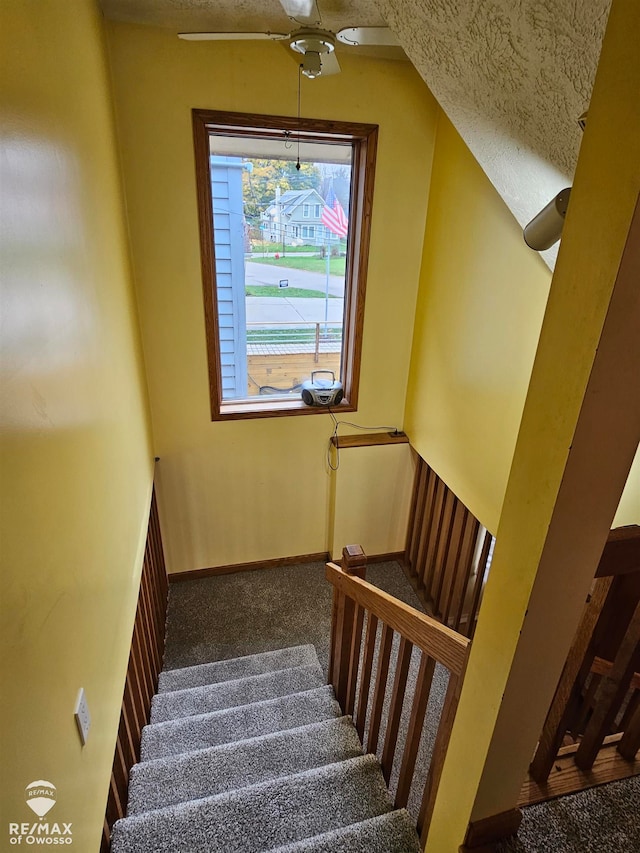 stairs featuring carpet, a textured ceiling, vaulted ceiling, and ceiling fan