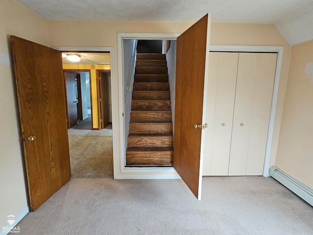 stairway with a textured ceiling, carpet, lofted ceiling, and a baseboard heating unit