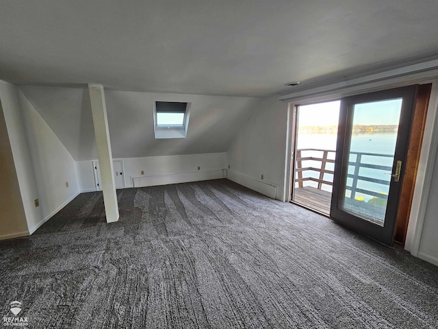 bonus room featuring dark carpet, a water view, and lofted ceiling with skylight