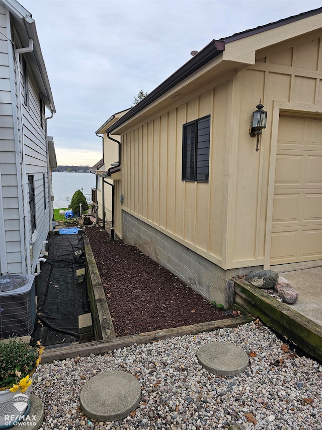 view of side of property with a water view and central AC unit