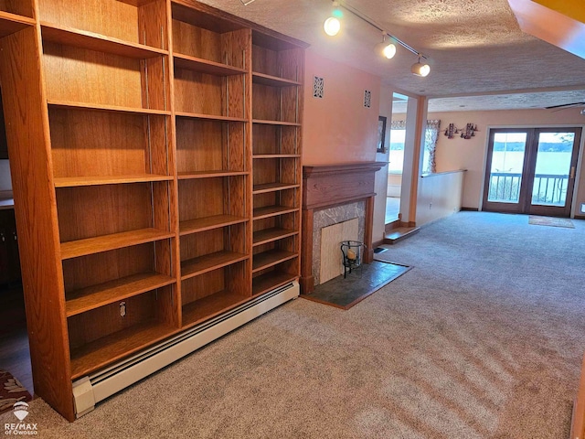 unfurnished living room with a fireplace, carpet, a textured ceiling, and a baseboard heating unit