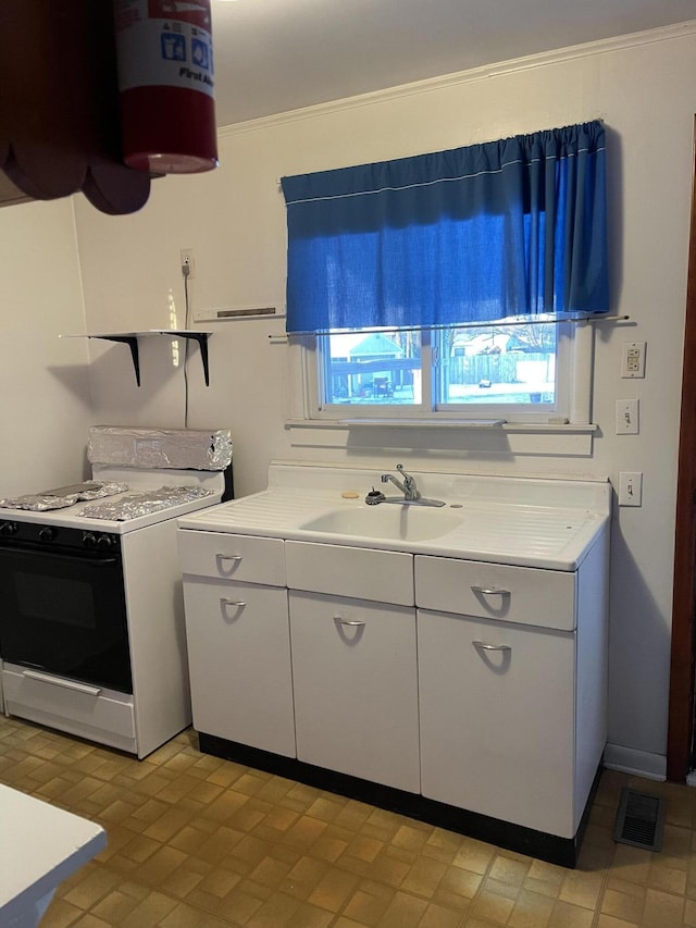 kitchen with sink, white cabinets, and white stove